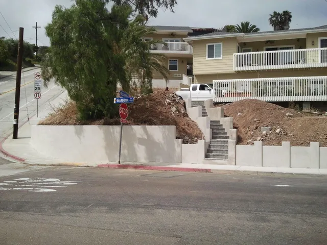 Finished stucco-faced block wall stepping along a corner lot.