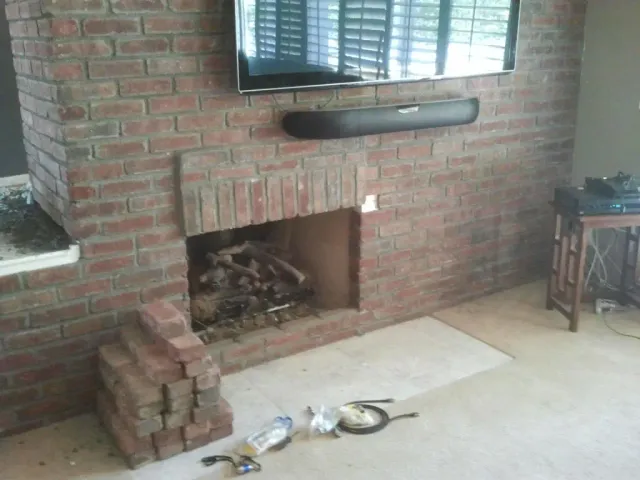 An older brick fireplace with a worn hearth, before repair.