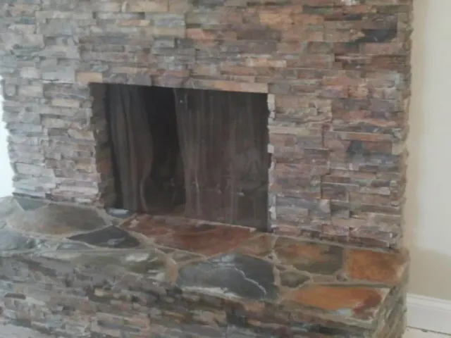 Irregular natural flagstone set in mortar on a raised hearth beneath a stacked-stone fireplace surround.