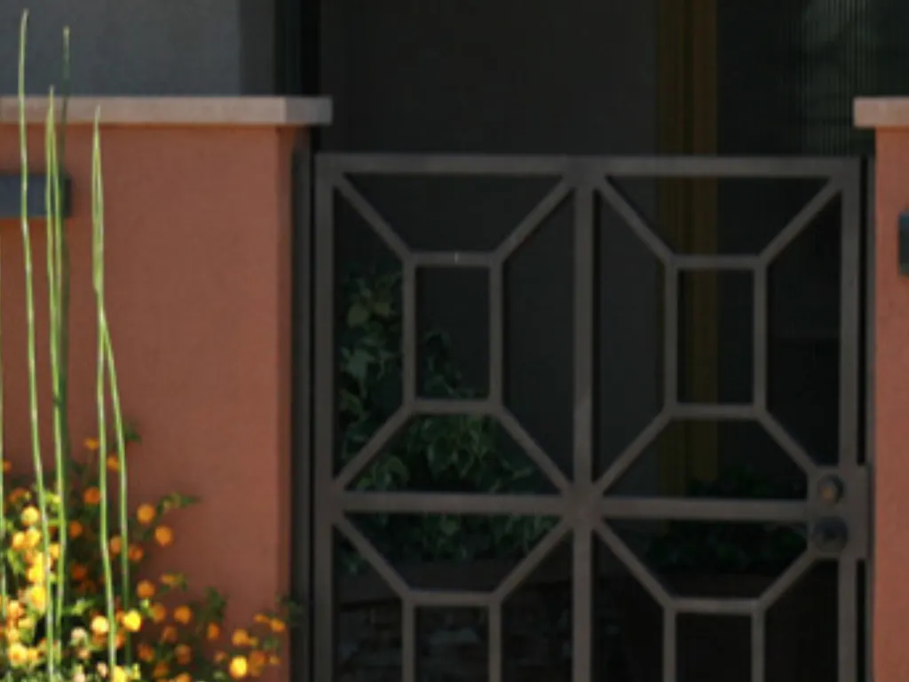 Stucco-finished block wall pilasters with stone caps flanking a decorative wrought-iron entry gate.