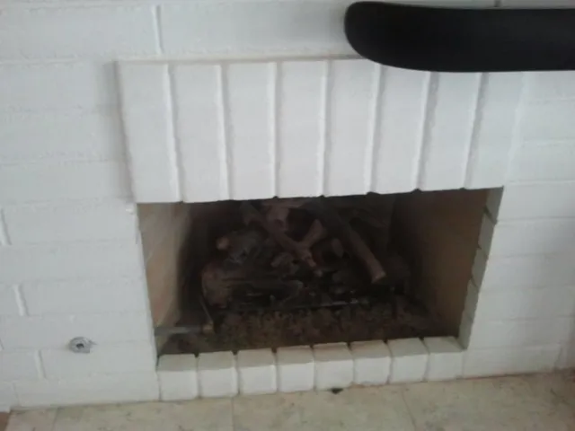 A brick fireplace refinished in white with a rebuilt hearth course.