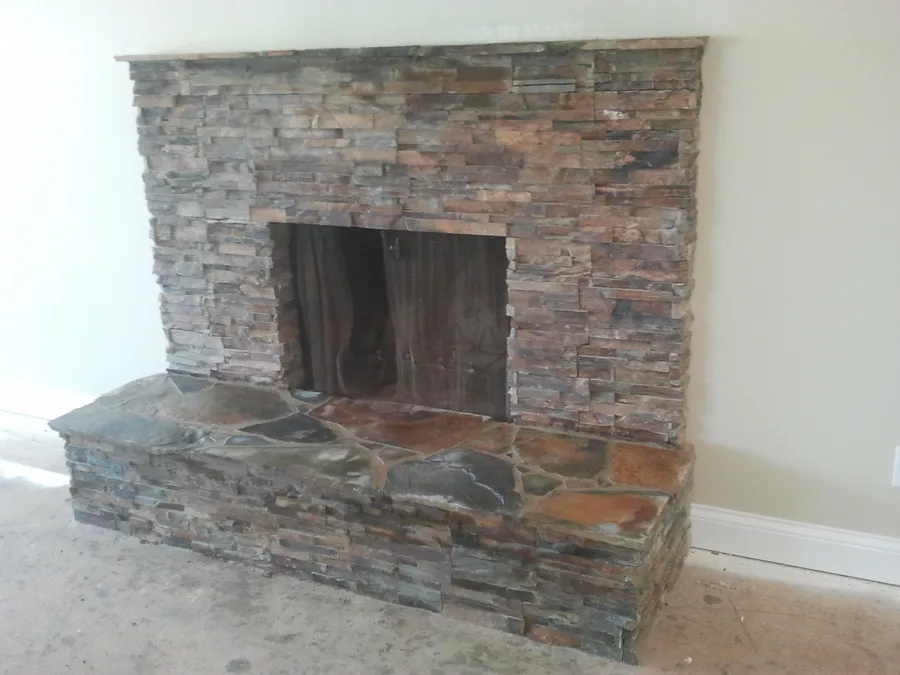 Stacked natural stone fireplace surround with a raised flagstone hearth.