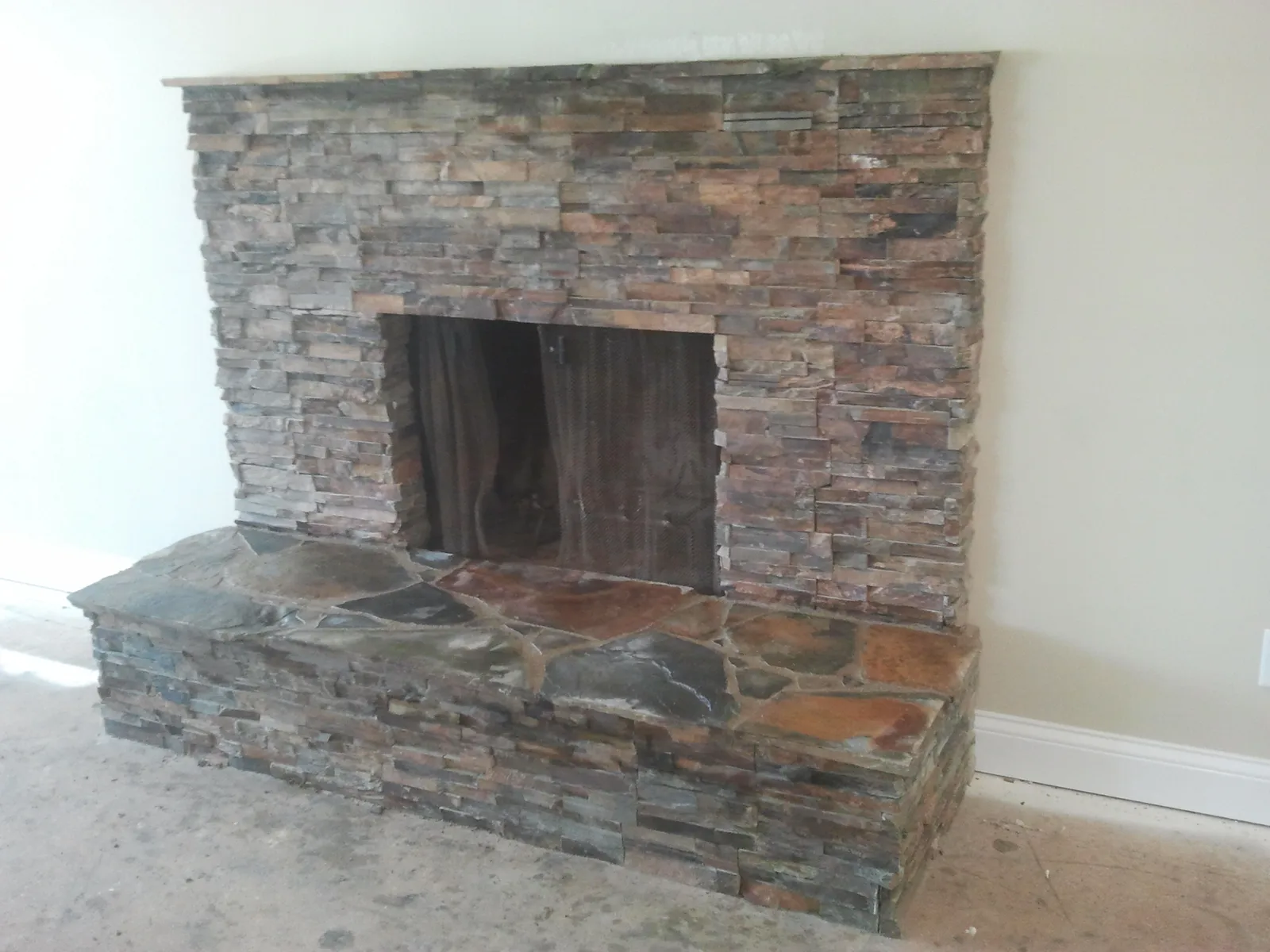 Stacked natural stone fireplace surround with a raised flagstone hearth.