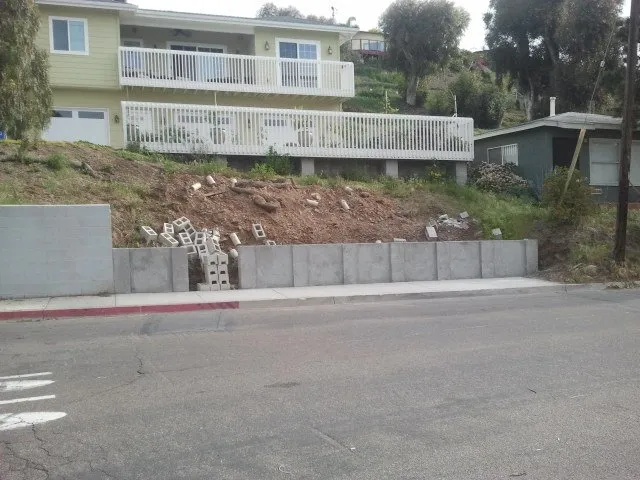 Existing low walls and an overgrown slope along the street before work began.