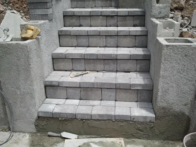 Close-up of grey paver treads set between plastered block stair walls.
