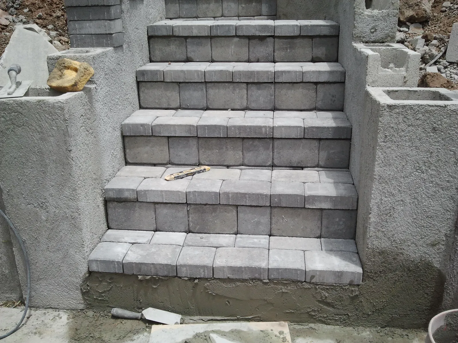 Close-up of paver stair treads set level between plastered block stringer walls on a San Diego hillside job.
