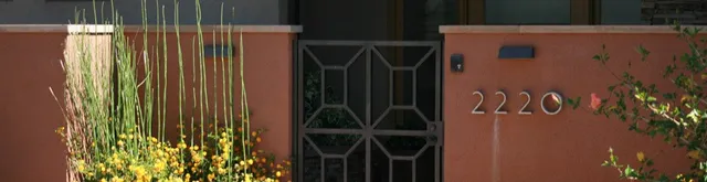 Stucco masonry pilasters framing a wrought-iron entry gate.