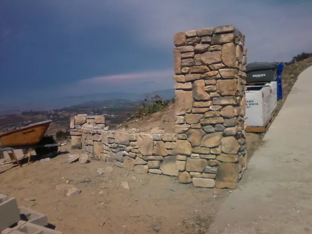Tall stone pillar with a mailbox beside the driveway.